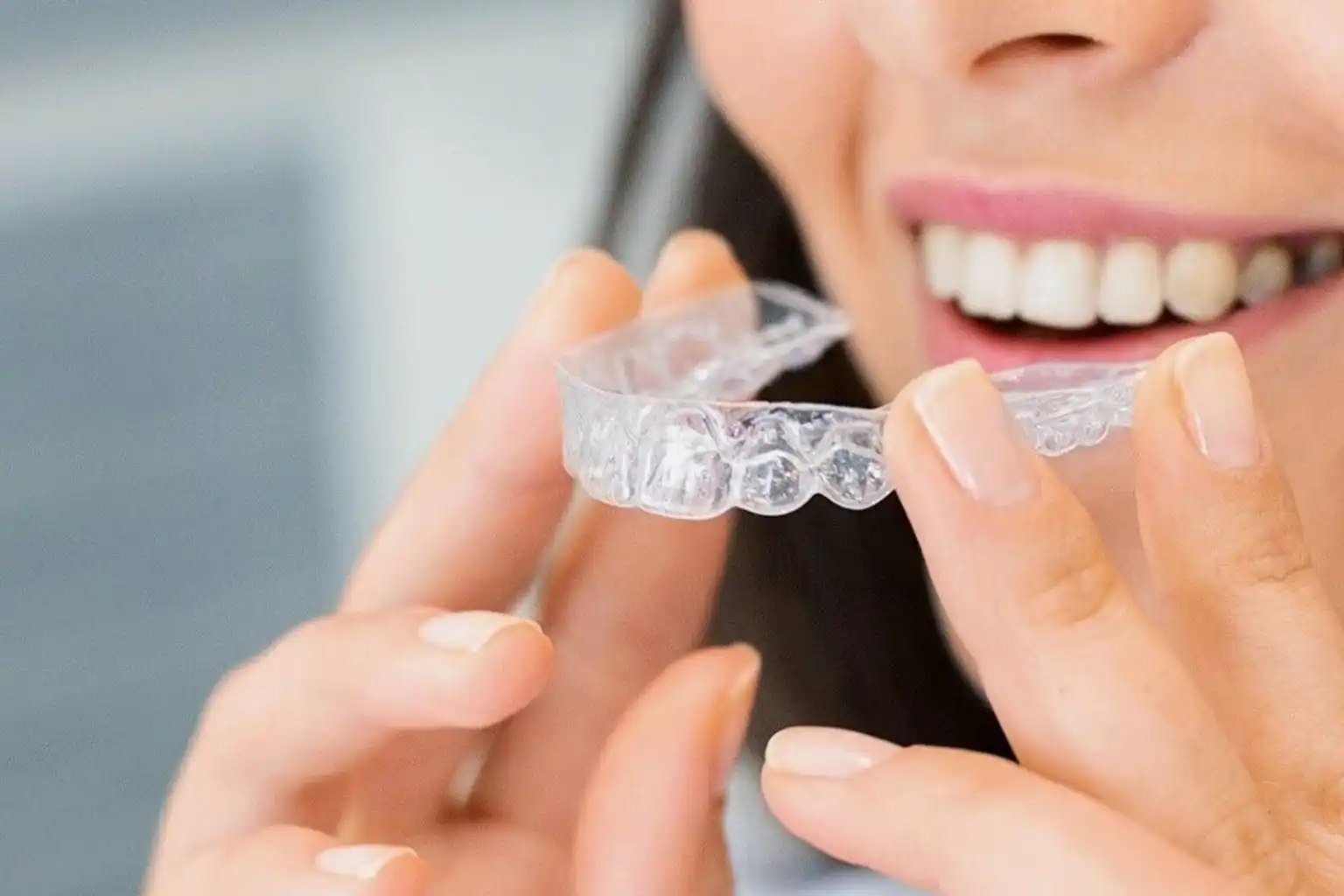 An adult holding a clear aligner tray before starting Invisalign treatment